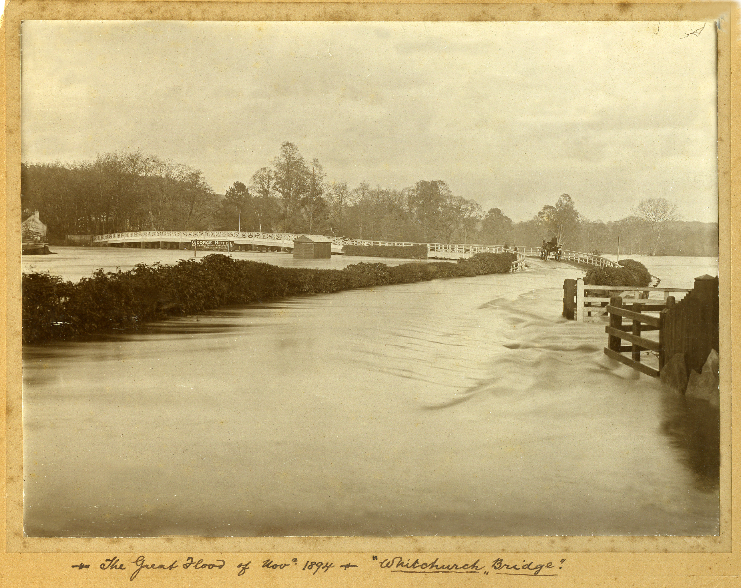 Black and white photograph of Whitchurch Bridge covered in water, a horse and carriage can be seen attempting to cross the bridge