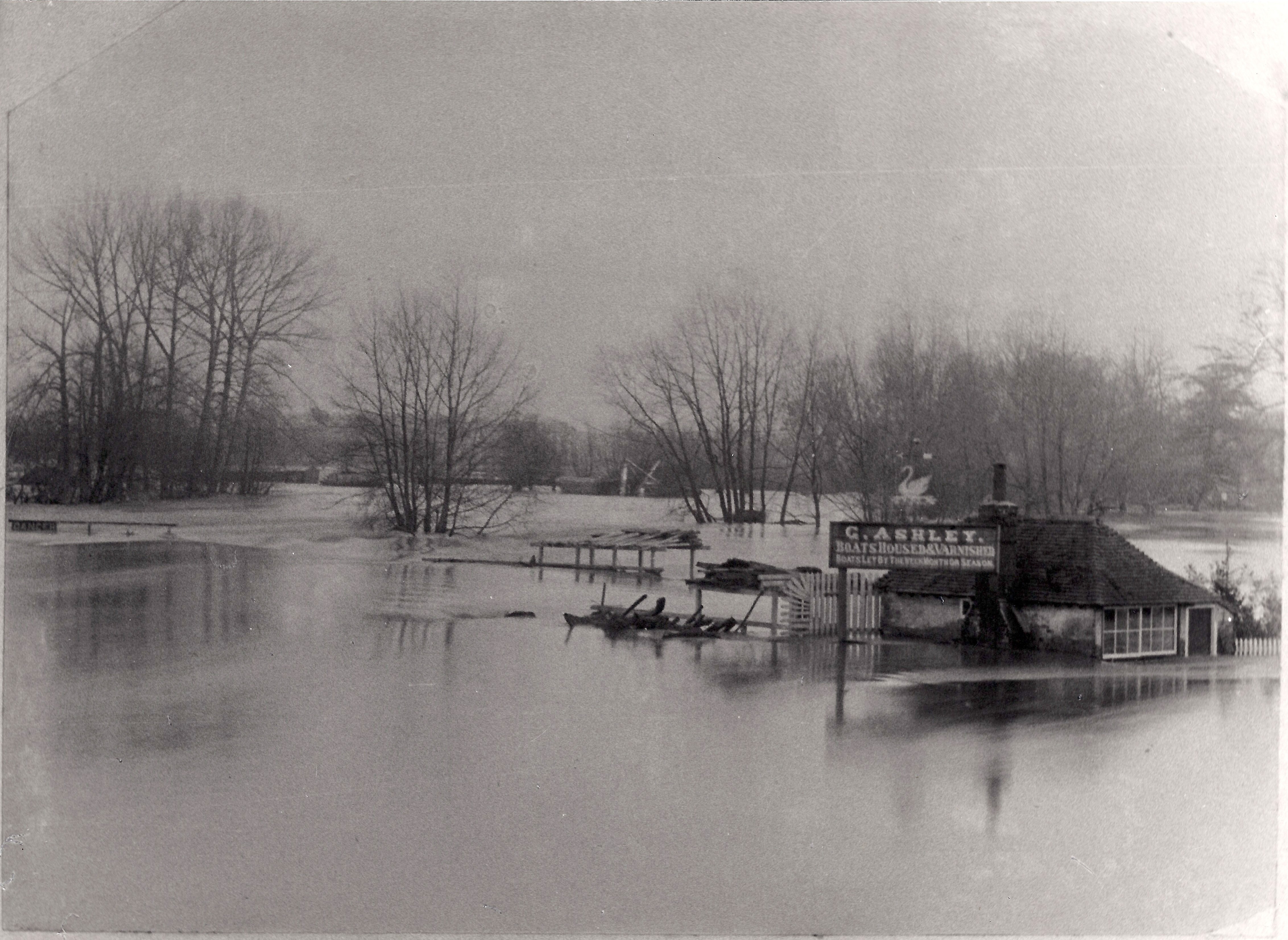 Black and white photograph of Whitchurch Weir submerged under water with only the roof of a nearby building visible