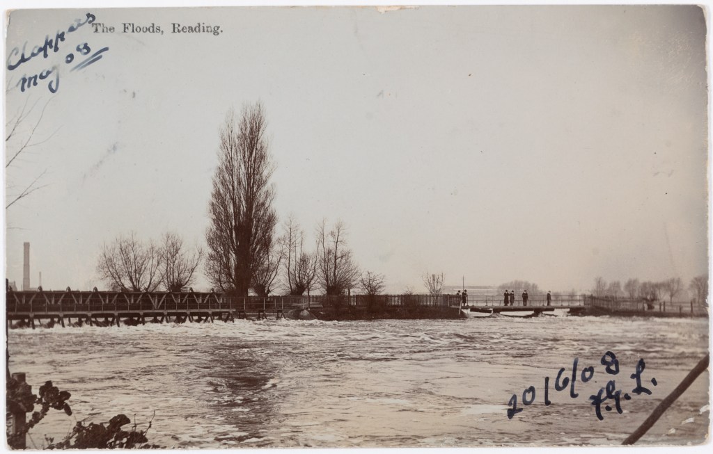 Black and white photograph of Caversham Bridge with people on, the water level is extremely high.