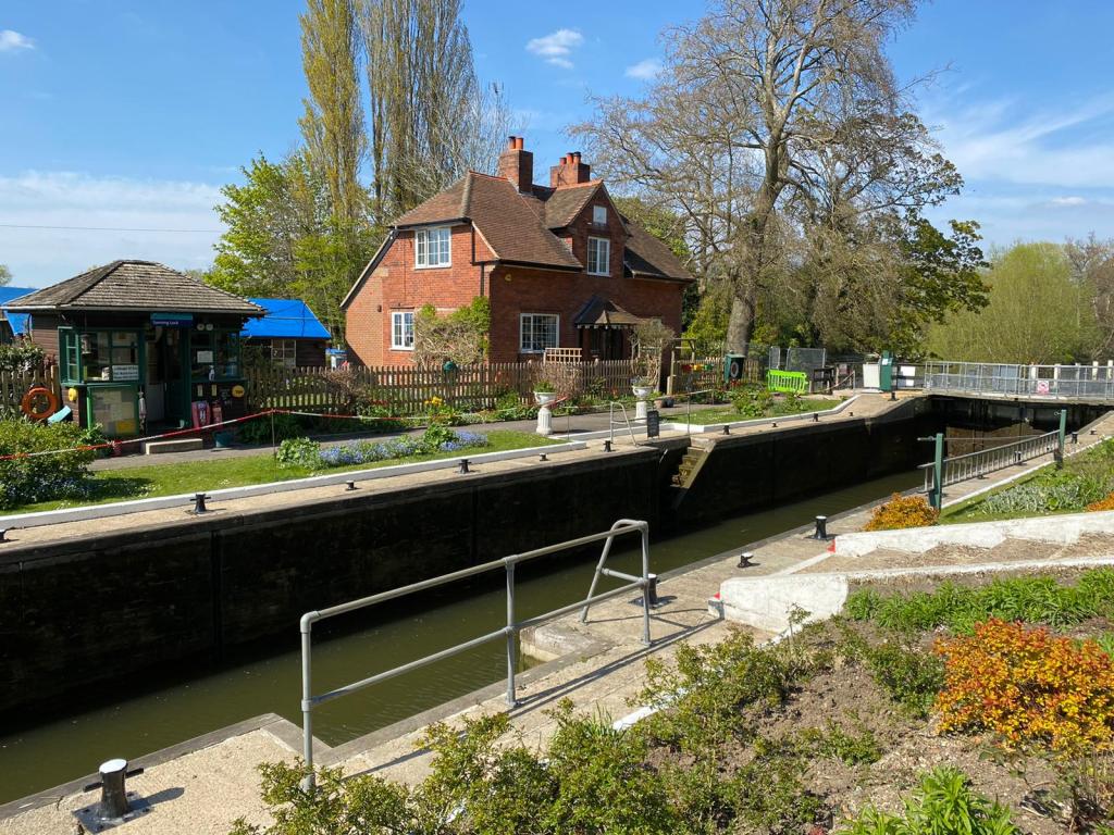 A brick house next to a lock on a sunny day with a large tree to the right of the house.